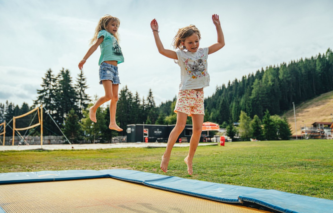 Mädchen haben Spaß beim Trampolin-Springen im Spielplatz am Badesee