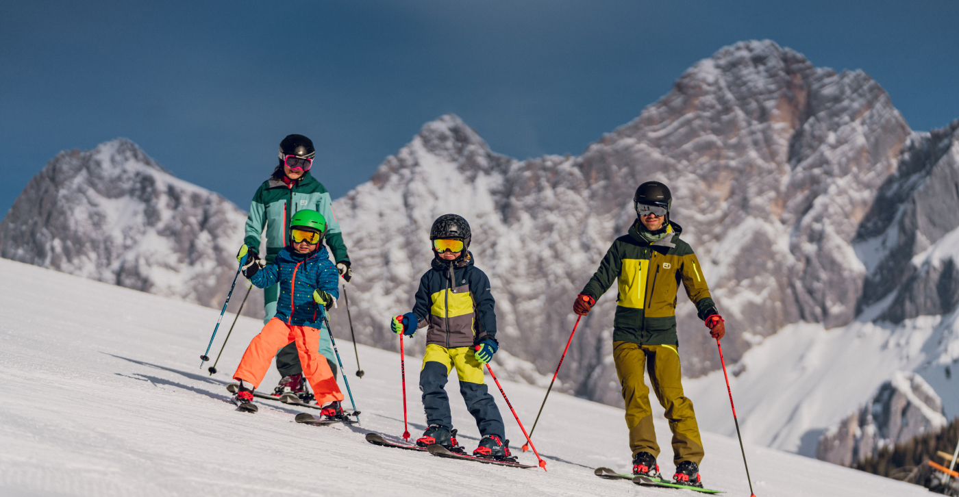 Skifahrer mit Kind auf der Skipiste in der Skiregion Ramsau am Dachstein