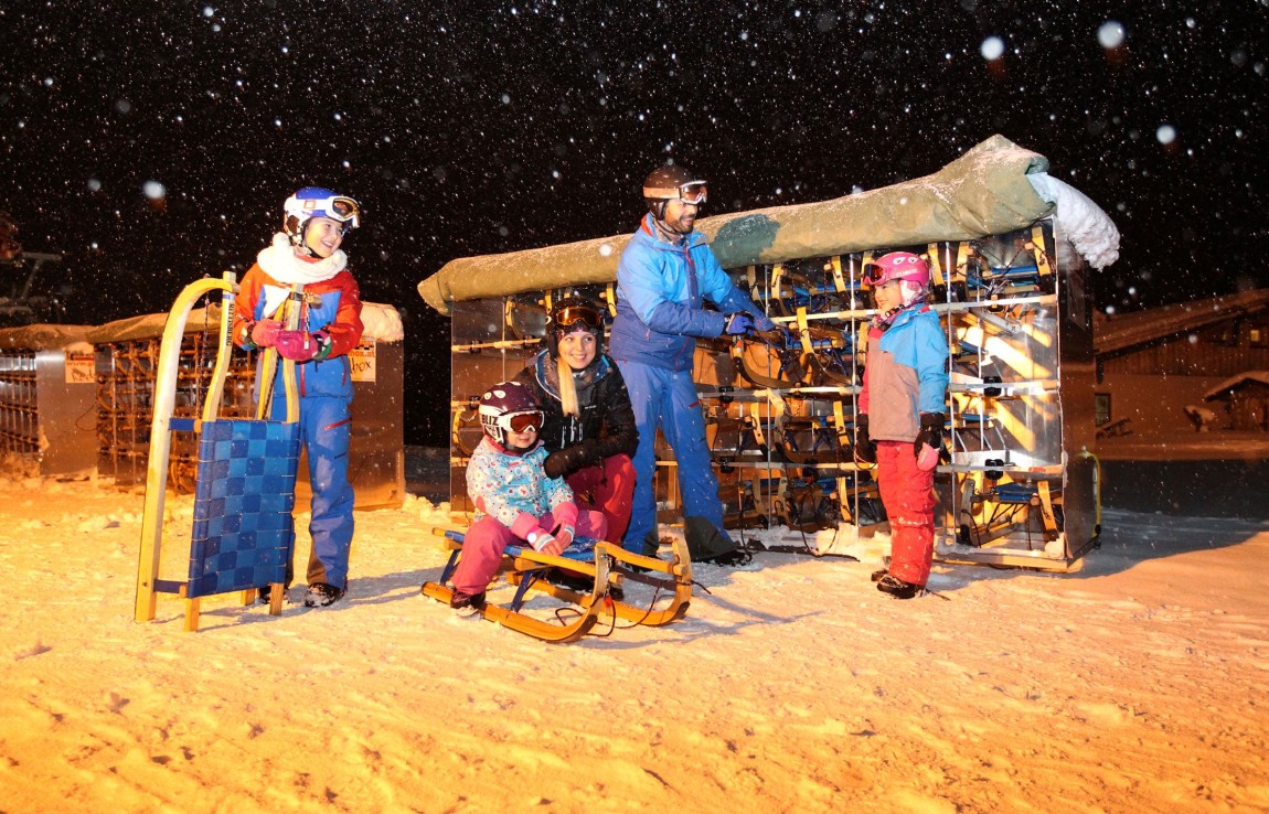 Familie mit Kind beim Rodelverleih für das Nachtrodeln am Rittisberg