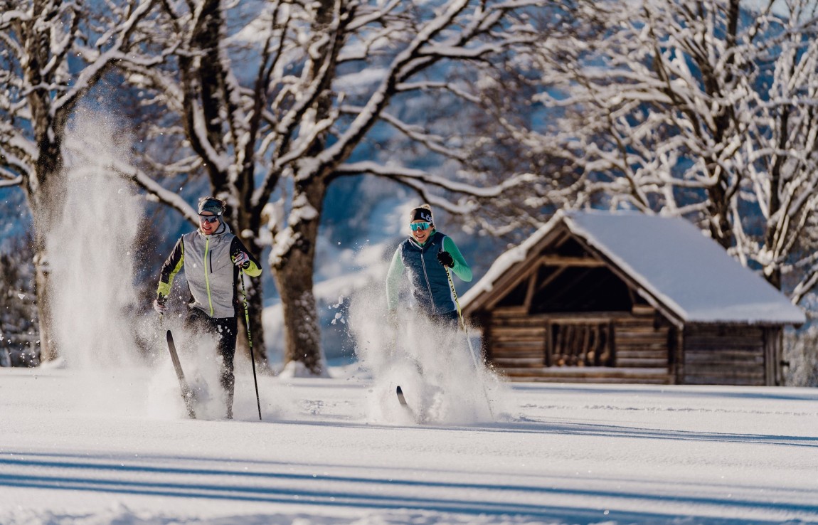 Im Urlaub mit den Langlaufskiern durch tief verschneite Landschaften in der Ramsau langlaufen