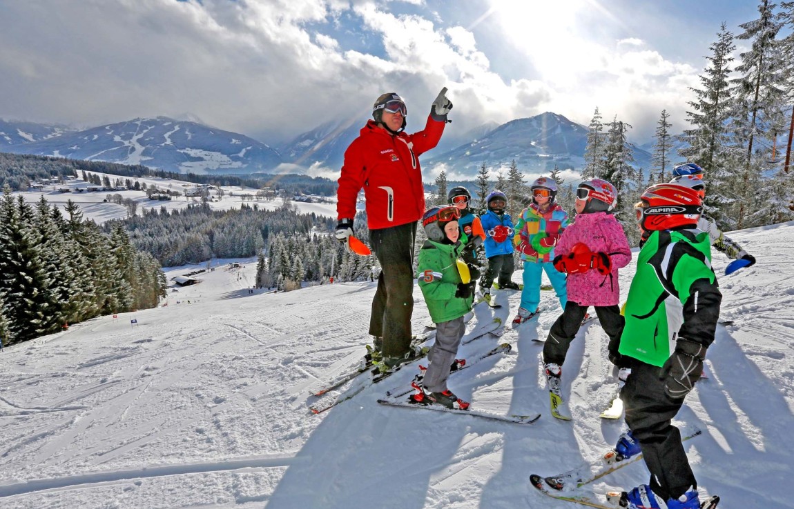 Skilehrer auf der Piste mit Kinder-Gruppe