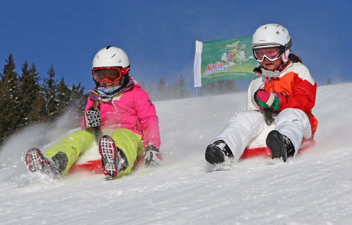Zwei Kinder flitzen mit dem Zipfelbob am Drachenlift